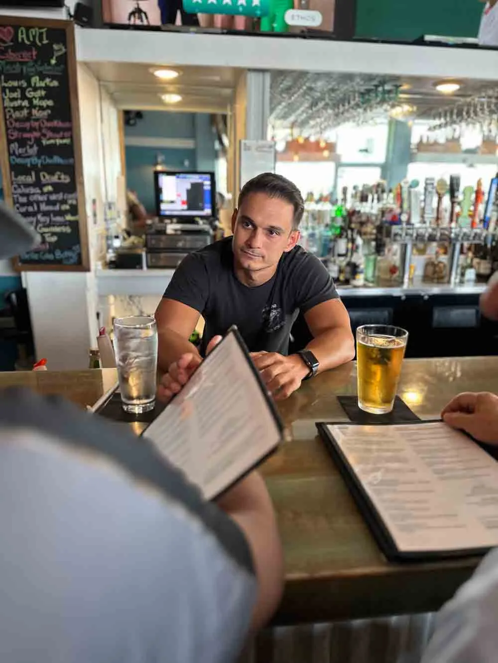 Bartender behind the bar at Hurricane Hanks, with the beer taps and guests reading menus