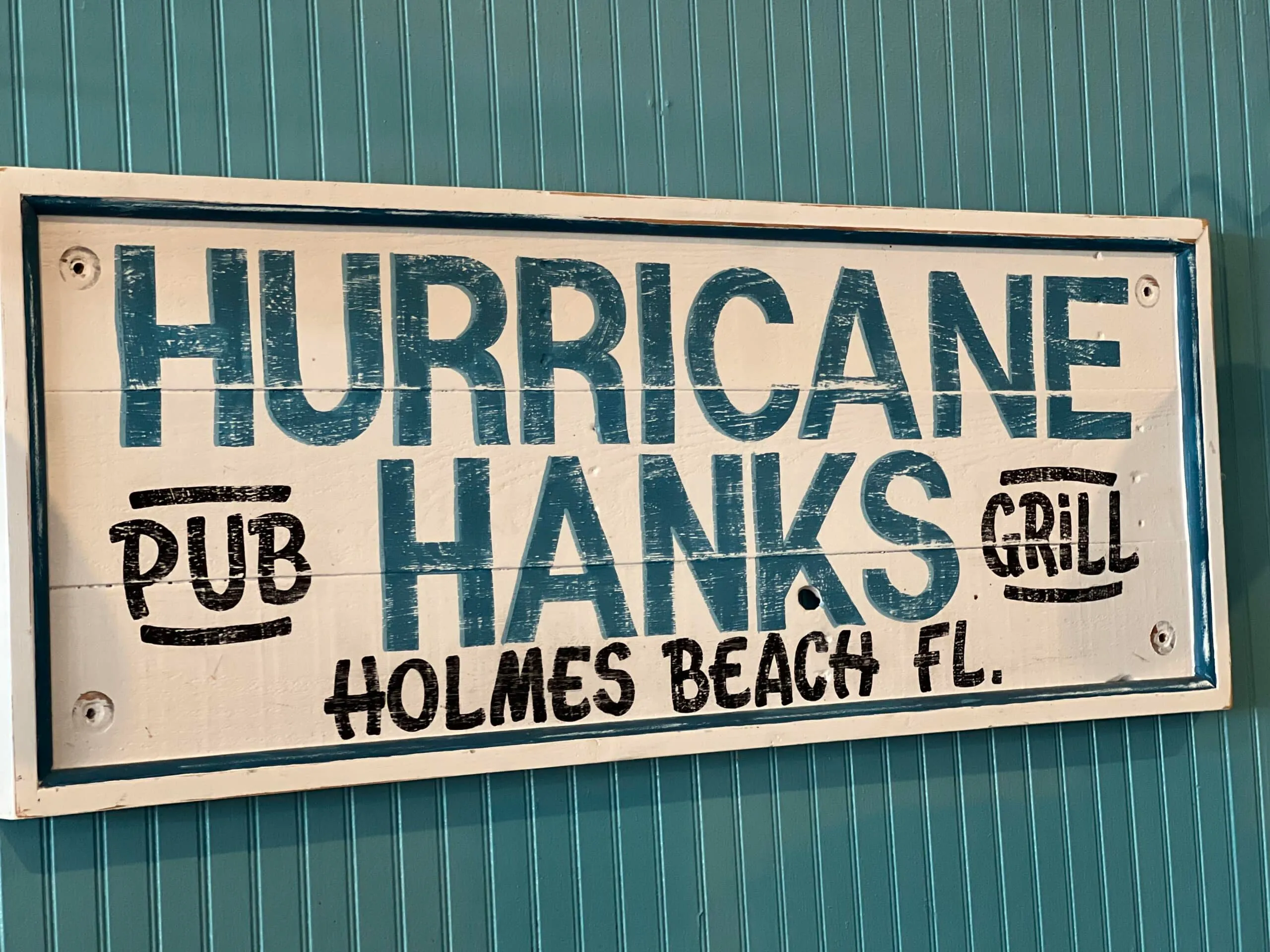 Hand-painted Hurricane Hanks Pub & Grill sign on the restaurant’s teal wall